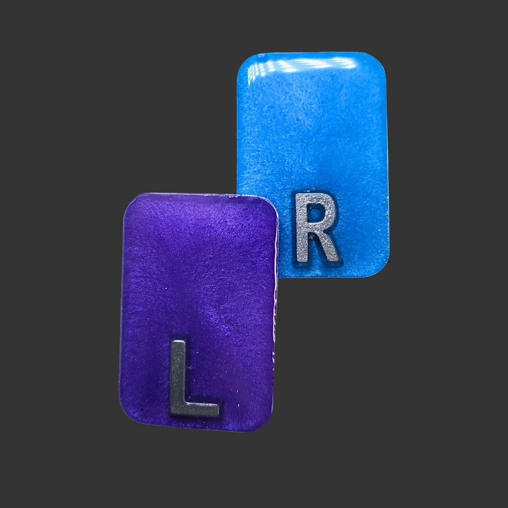 Purple and blue see-through X-ray markers with silver glitter, designed for radiographers, placed on a clean background