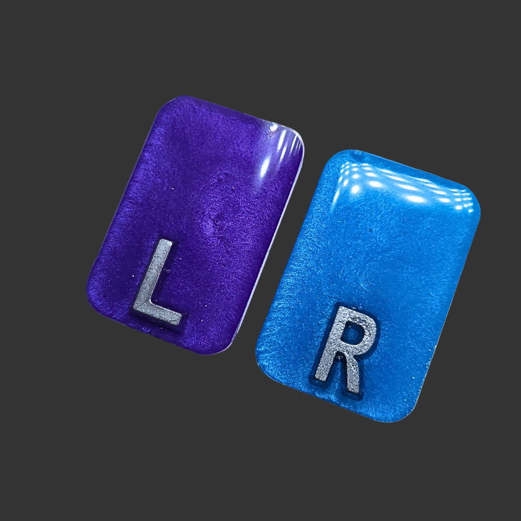 Purple and blue see-through X-ray markers with silver glitter, designed for radiographers, placed on a clean background