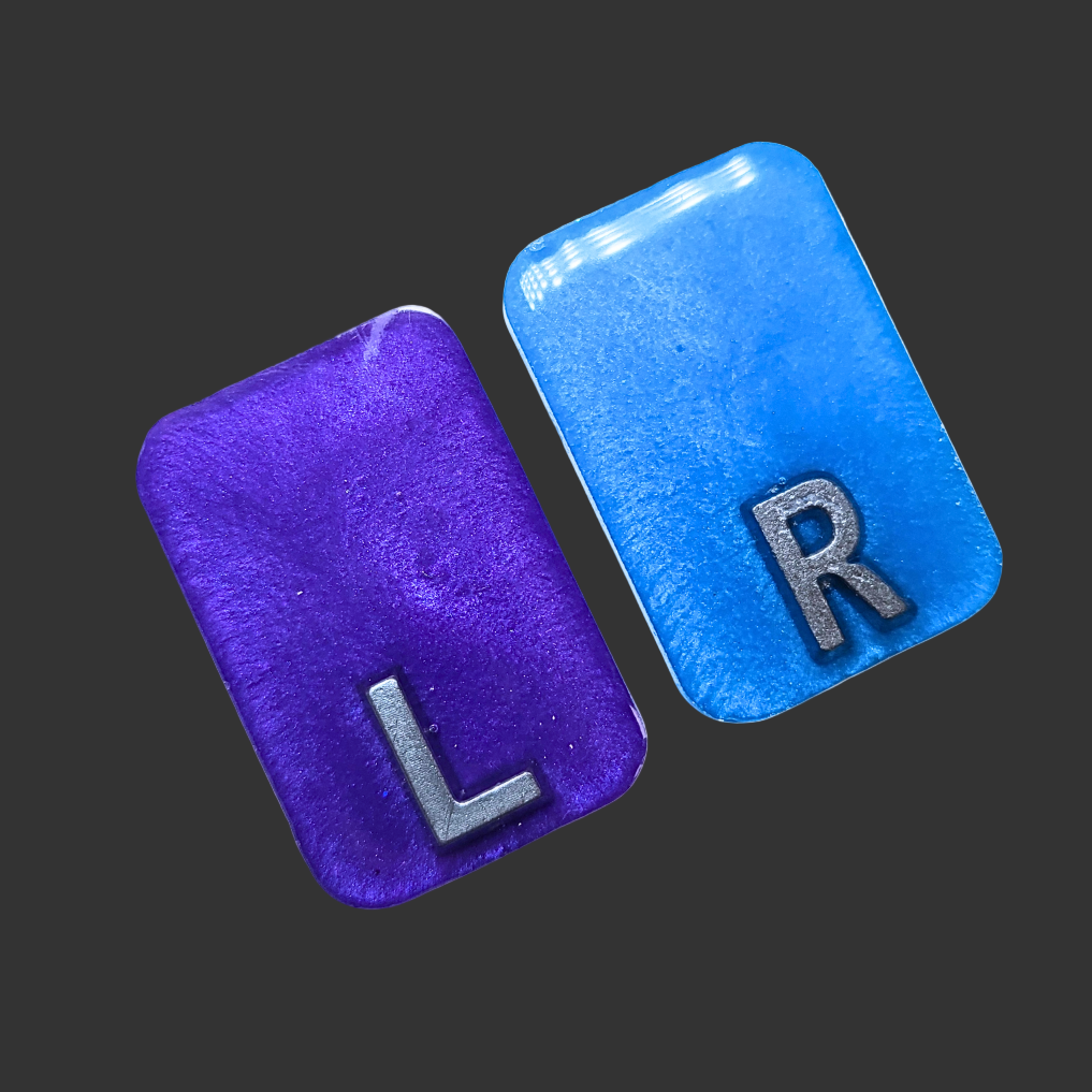 Purple and blue see-through X-ray markers with silver glitter, designed for radiographers, placed on a clean background