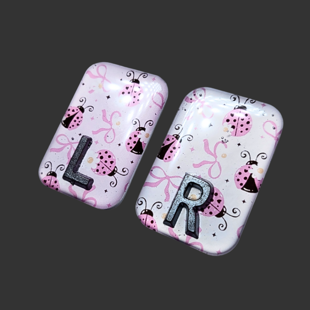 Pink, black, and white ladybug-themed X-ray marker with customizable initials
