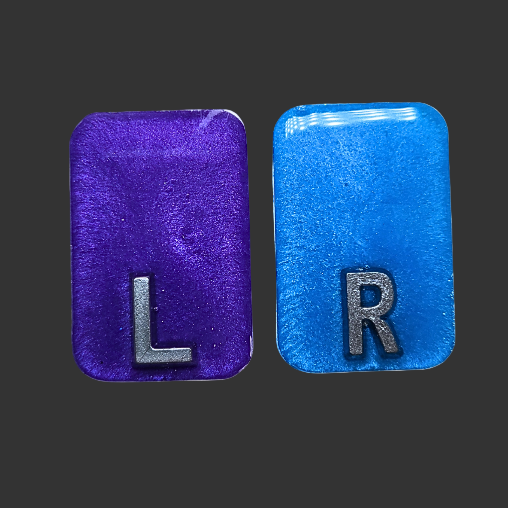 Purple and blue see-through X-ray markers with silver glitter, designed for radiographers, placed on a clean background
