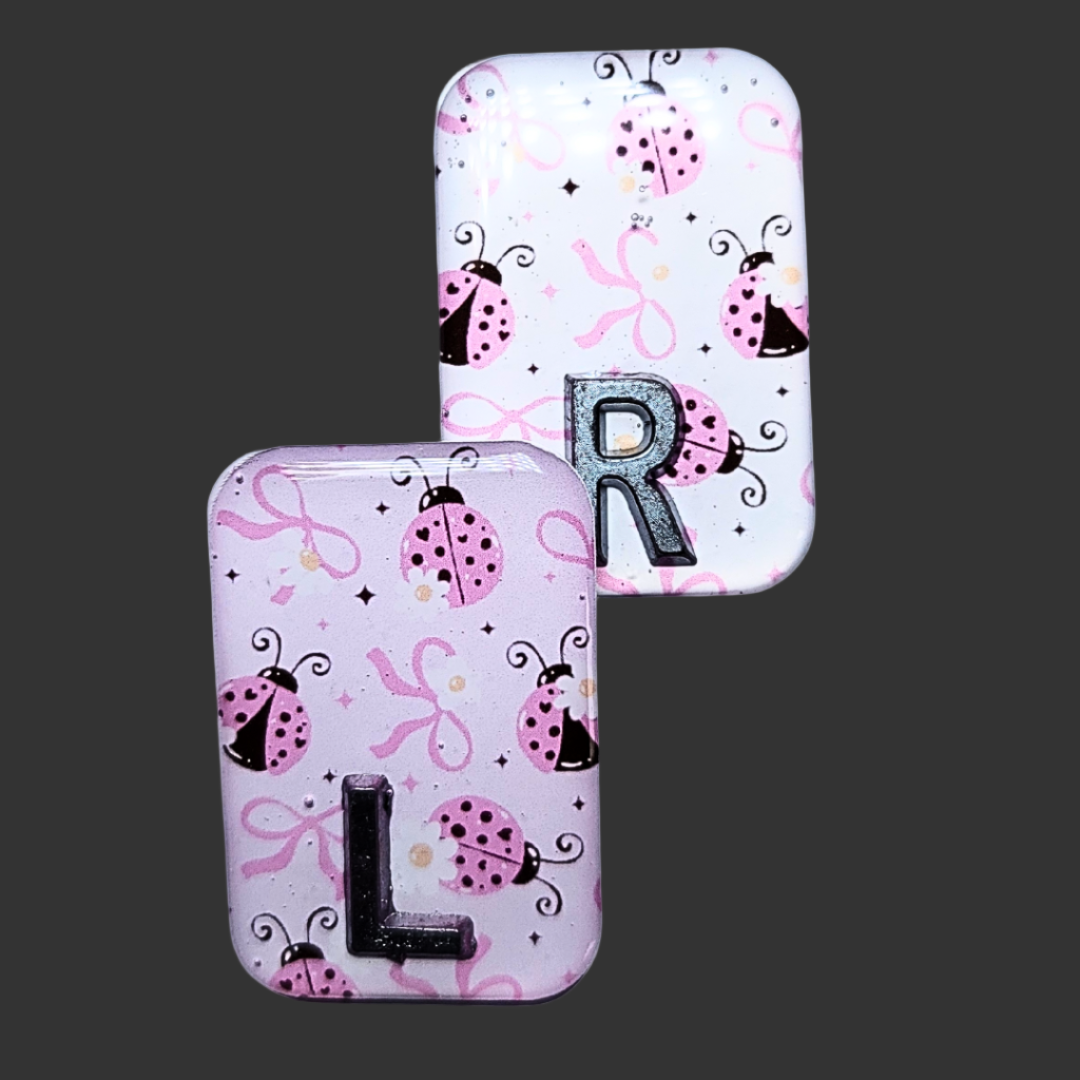 Pink, black, and white ladybug-themed X-ray marker with customizable initials